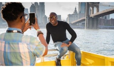 One man takes a photo of another with a city in background